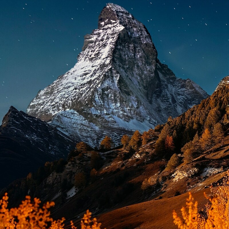 Snow-capped mountain peak under a starry night sky.